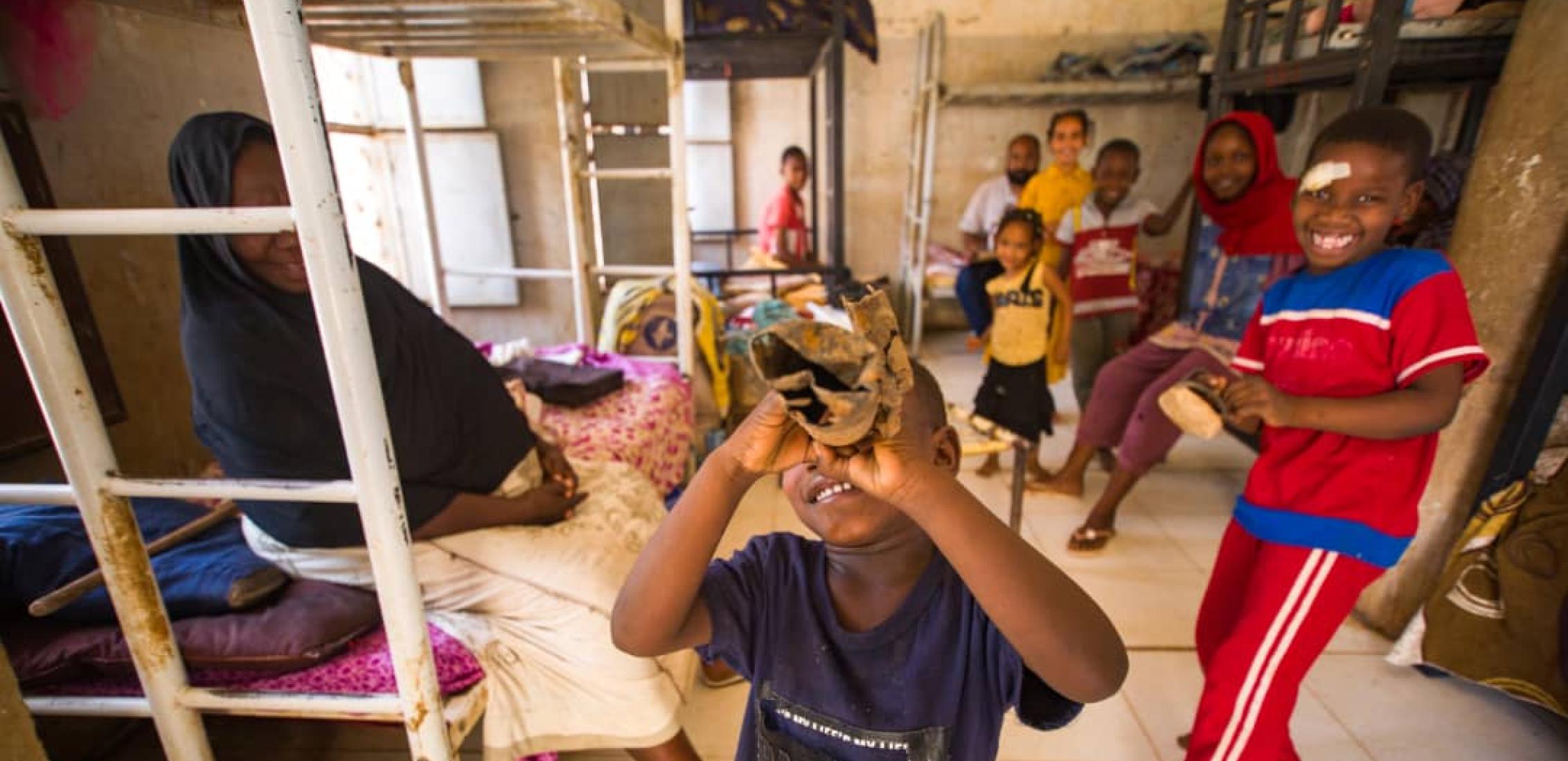 UN0844235/Mohamdeen On 12 May 2023, displaced children pose for a portrait at a temporary shelter. Following continued fighting that broke out in Khartoum on 15 April, children and their families have fled and sought safety in neighbouring safer states. 